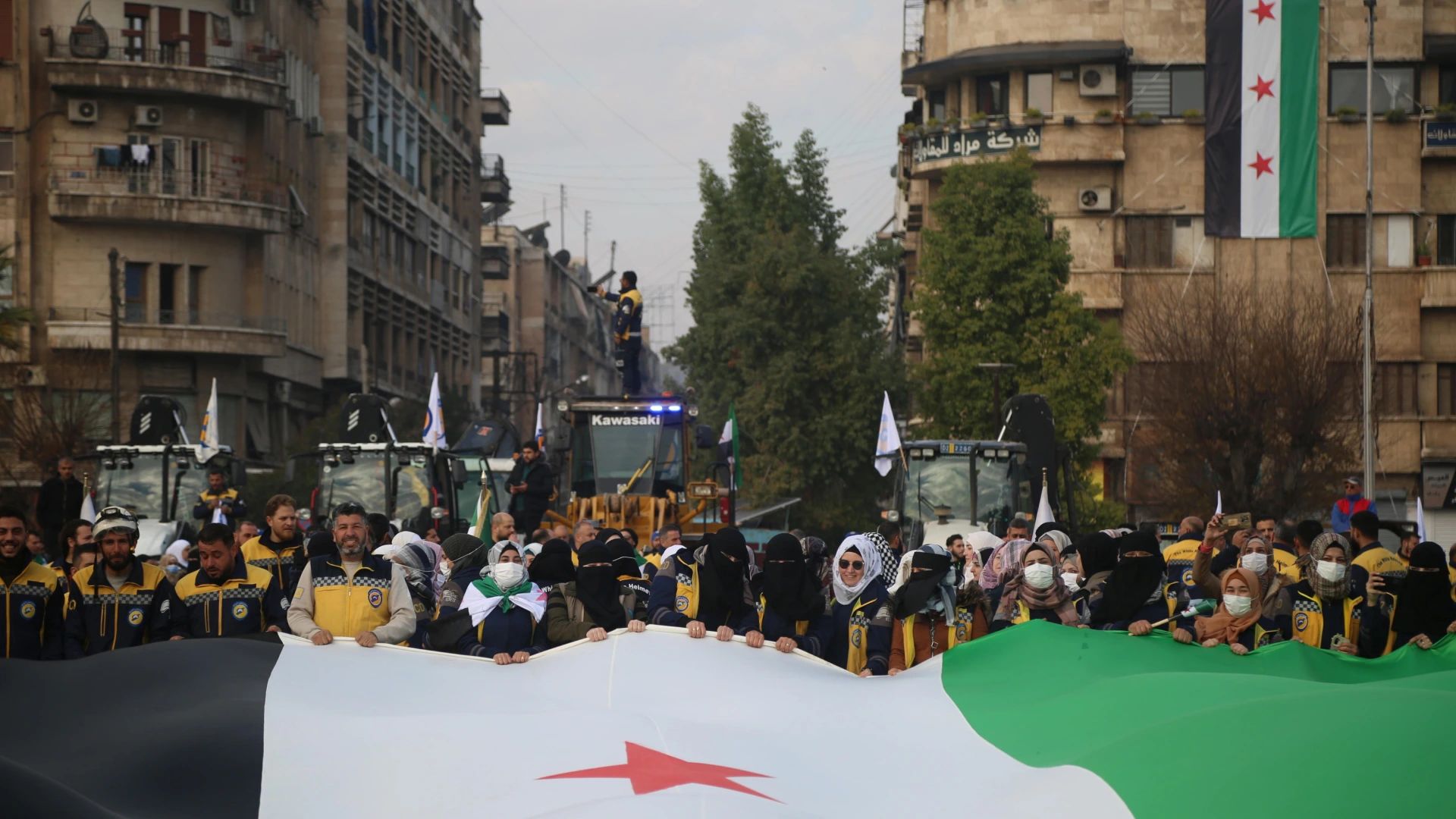  Alep (República Àrab Síria), 25/12/2024.- Membres dels Cascos Blancs, un grup de Defensa Civil Síria, i altres voluntaris sostenen una gran bandera de l’oposició siriana durant una trobada per anunciar l’inici de la campanya de reparació "Tornem, Alep". L'objectiu de la campanya és revitalitzar diversos barris de la ciutat mitjançant la neteja de carrers, la cura d'arbres, la pintura de murals i la neteja d'instal·lacions públiques. (Síria) EFE/EPA/BILAL AL HAMMOUD